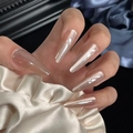 Close-up of champagne cat-eye almond press-on nails with luxury silk fabric background - By1648 Moonlight Girl / Glue Type