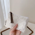 Dettaglio del ricamo in pizzo floreale bianco su un portamonete in cotone con etichetta - Portamonete