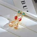 Makroaufnahme luxuriöser goldener Ohrringe mit himmelblauen, rosenroten und champagner Edelsteinen - Champagner