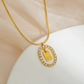 Macro detail of gold snake chain with paved diamond oval pendant featuring letter G - Letter G