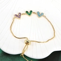 Detailed shot of golden heart bracelet with colorful zircons on shell tray - Purple/Green/Sky Blue (BR10803-6)