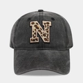 Close-up of washed black denim baseball cap with leopard print letter N embroidery detail - Letter N