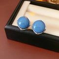 Close-up of blue cabochon stud earrings with silver frames inside a black jewelry box - Silver Earring Post-Blue