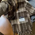 Détail d'une écharpe à carreaux avec motifs marron vintage et fines franges - café
