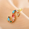 Macro detail of gold S-letter pendant with multi-colored crystals on soft fabric - Letter S