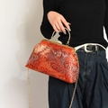 Retro red handbag with phoenix texture and gold rhinestone clasp shown with a model - Red