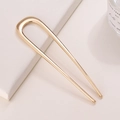 Detail van een minimalistische goudkleurige metalen U-vormige haarspeld op wit decor - Gladde Glanzende Stijl / Goud