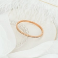 Detail of rose gold bangle with pave-set zircons on white feathers and stone tray - Rose Gold