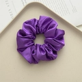 Elegant purple satin scrunchie hair tie with smooth glossy finish on a beige tray - Deep purple