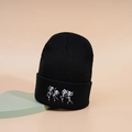 Schwarze Strickmütze mit weiß bestickten tanzenden Skeletten auf dem modischen Umschlag - Schwarz