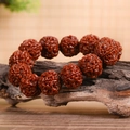 Deep reddish-brown Rudraksha seed bracelet with natural textures on a wooden base - Jade-like 20mm 5-Valve (With Spare Beads)