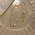 Dettaglio collana di perle dorate con ciondolo a barra curva su piatto in ceramica - Oro (Perla Singola)