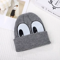 Gray knitted beanie for kids with large cartoon eye patches on a stylized background - One Size / Gray
