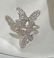 Vista detallada del anillo de doble mariposa con circonitas brillantes sobre satén blanco - Plateado