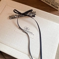Dettaglio ravvicinato di un'elegante clip per capelli in raso nero con cristalli lucidi - Molletta a becco d'anatra in cristallo con fiocco a nastro lungo nero / Pezzo Singolo / Nero