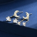 Elegante set di orecchini dorati a forma di luna, stella e zircone su sfondo blu scuro - Oro