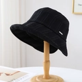 Black plaid bucket hat with silver metal tag on a wooden stand in a home setting - 80846 Black