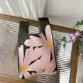 Close-up of green knitted tote bag with pink flower pattern on a glass table - Cottonseed Pollen
