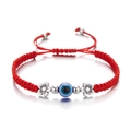 Macro shot of red woven rope bracelet with blue evil eye and silver floral beads - Flower / Red