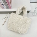 Primer plano de bolso tote de felpa Sherpa blanca con etiqueta Sozakka en un escritorio - Blanco Roto