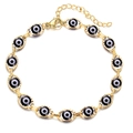 Close-up of golden Evil Eye bracelet featuring blue enamel eyes and adjustable lobster clasp - Bracelet/Anklet / Gold Base Black