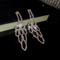 Macro shot of rose gold tassel earrings with sparkling rhinestones on dark background - Gold
