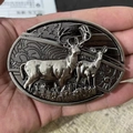 Detailed close-up of oval vintage silver belt buckle with embossed deer and flag design - Elk