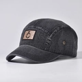 Detail van zwarte gewassen denim pet met bruine patch en bronzen metalen ring detail - Zwart