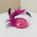 Detailweergave van roze fascinator met elegante veren en een bloem van parels detail. - Rozerood