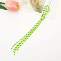 Detail of green woven cord phone strap with black speckles on a white surface - Green