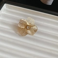 Close-up of golden hollow flower necklace pendant with rhinestone center on jewelry tray - Ring - Gold