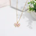 Elegante collar de lazo dorado con circonitas rosas sobre fondo de mármol blanco - Lazo Oro Rosa