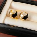 Close-up of golden round hoop earrings with black enamel on a beige velvet jewelry box - 25# Black Zirconia Enamel Ear Clip (Real Gold Plated)