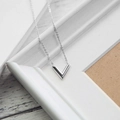Minimalistische V-vormige ketting in zilver op een witte houten achtergrond - O113 Gebogen V-ketting Zilver