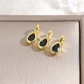 Macro shot of three teardrop pendants with black stones in 18k gold-plated frames - Black
