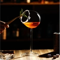 Elegant bird-shaped cocktail glass with orange drink and rosemary garnish in a bar - Zombie Shape Goblet