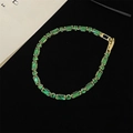 Elegant gold bracelet with emerald green gemstone on a black background - Gold Bracelet with Green Zircon