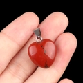 Pendentif cœur en jaspe rouge avec veines naturelles tenu à la main sur fond noir - Jaspe Rouge