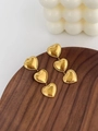 Detailed close-up of golden triple-heart earrings on a wooden tray with bead edge texture - Triple Heart Dangle Earrings