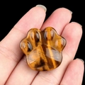 Tiger Eye stone cat paw figurine held in palm showing natural silk luster and texture - Tiger's Eye