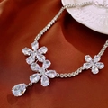 Macro shot of silver zircon flower necklace with drop pendant on red satin fabric - Silver Flower Teardrop Necklace