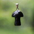 Black obsidian mushroom pendant with silver metal clasp on a natural green background - Obsidian