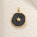 Detail of a round gold pendant with black enamel inlay and a tiny gold star charm - Black Star