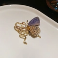 Dettaglio macro di spilla a farfalla con ala in maglia viola e serpente di diamanti - Forma Farfalla Serpente / Oro/Viola
