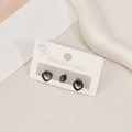 Detail view of black stainless steel heart and crystal stud earrings on white card - Hollow Heart Style / Black