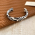 Macro shot of black and white woven leather open cuff bracelet on textured backgrounds - Black and White Zebra Pattern Narrow Style / Black