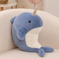 Plush narwhal toy with golden horn and soft blue fur on a cozy cream sofa - Narwhal