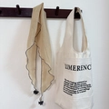 Close-up of a beige thin triangular scarf with wave edges hanging on a wooden wall hook - Turmeric