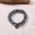Close-up of sparkling blue faceted crystal hair tie with a gold metal brand pendant - Blue