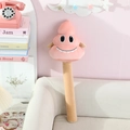 Nahaufnahme des rosa Plüsch-Kot-Hammerschlägers mit lachendem Gesicht im Wohnzimmer - Rosa
